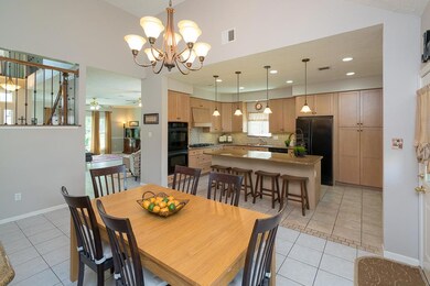 This bright and airy eat-in breakfast room is open to the kitchen, stair landing, and family room and boasts a high ceiling, 9 light oil rubbed bronze chandelier, built-in coffee station, and wide picture window with bench seat and backyard views.