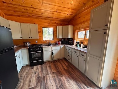 Kitchen featuring black appliances, lofted ceiling