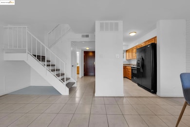 Kitchen with black appliances, light countertops, light tile patterned flooring, and brown cabinets