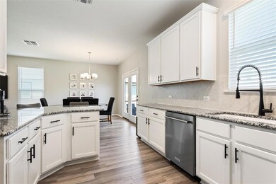 Kitchen with healthy amount of natural light, white cabinetry, and light stone countertops