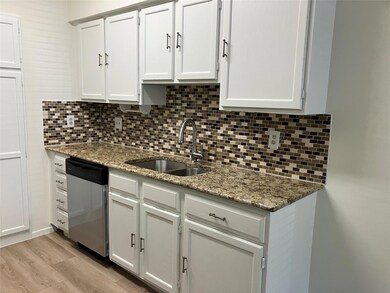 Kitchen with dishwasher, decorative backsplash, light stone counters, and white cabinets
