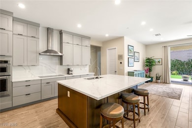 Kitchen with gray cabinetry, wall chimney exhaust
