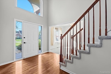 Entryway featuring healthy amount of natural light, wood-type flooring, a towering ceiling, and stairs
