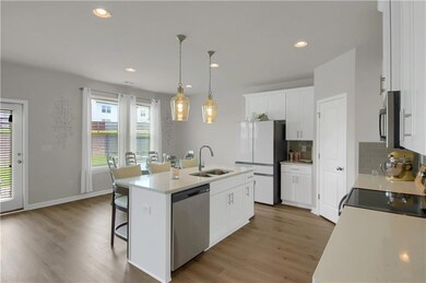 Kitchen featuring stainless steel appliances, light wood-style floors, decorative backsplash, a breakfast bar area, and recessed lighting