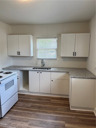 Kitchen featuring a sink, range, white cabinetry,