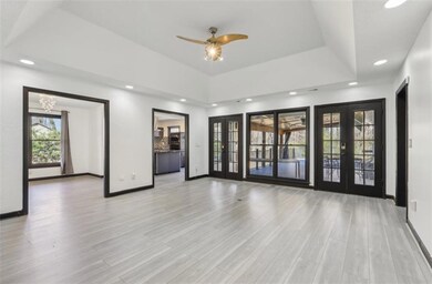 Spare room with wood finished floors, french doors, a raised ceiling, and baseboards