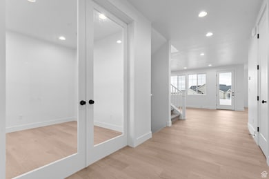 Corridor featuring recessed lighting, light wood finished floors, stairs, and french doors