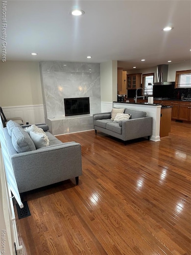 Living room featuring hardwood / wood-style floors, recessed lighting, a wainscoted wall, and a fireplace