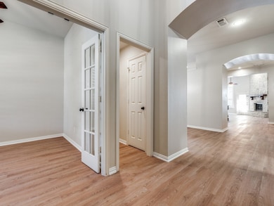 Corridor featuring arched walkways and light wood-type flooring