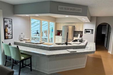 Kitchen with stone countertops, arched passthrough window, and bar seating for casual dining.