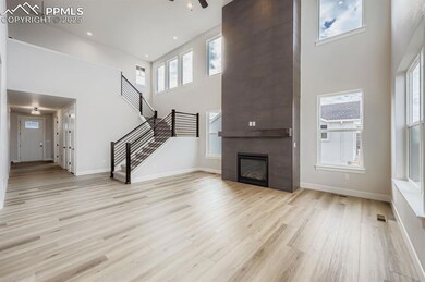Unfurnished living room with a high ceiling, a fireplace, healthy amount of natural light, light wood-style flooring, and a ceiling fan