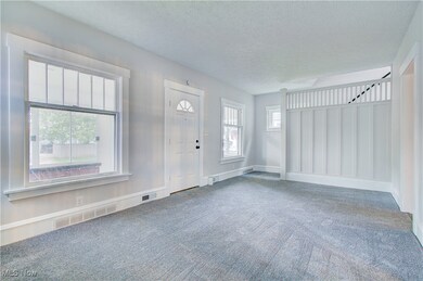 Foyer with carpet, a textured ceiling, and baseboards