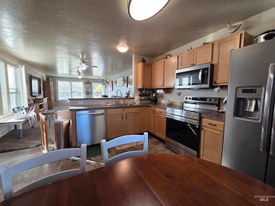 Kitchen with stainless steel appliances, a textured ceiling, open floor plan, a peninsula, and a ceiling fan