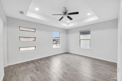 Empty room with a raised ceiling, light wood-type flooring, ceiling fan, and recessed lighting