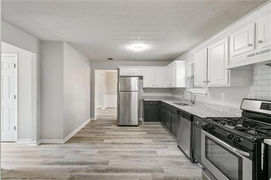 Kitchen featuring appliances with stainless steel finishes, a sink, custom range hood, white cabinetry, and light wood-style flooring
