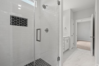 Full bathroom with a shower stall, vanity, and light marble finish floors
