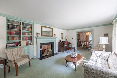 Living room featuring carpet, crown molding, a fireplace, and a notable chandelier