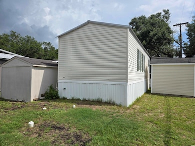 View of property exterior featuring a storage unit and a lawn