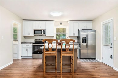 The Kitchen features a Large Island with Granite Countertops, White Shaker Cabinets, Stainless Steel Appliances, and Views to the Living Room