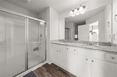 Full bath featuring double vanity, a stall shower, and wood finished floors