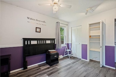 Bedroom with a textured ceiling, ceiling fan, a closet, and hardwood / wood-style floors