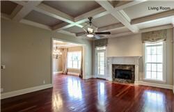 The living room features a fireplace, magninficent coffered ceiling, oversized windows and a beautiful fireplace.