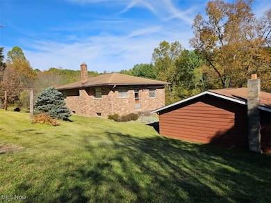 Rear view of house with a chimney, a lawn, and brick siding