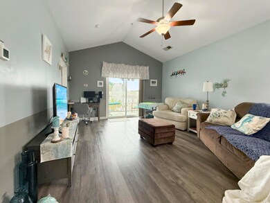 Living area featuring dark wood-type flooring, ceiling fan, visible vents, and high vaulted ceiling