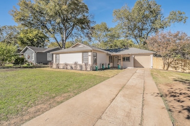 Single story home featuring concrete driveway, a front yard, a garage, and a shingled roof