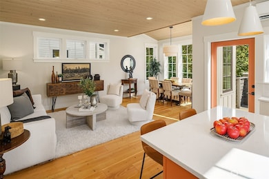 A warm paneled ceiling envelopes the gracious living and dining room that overlooks the lush garden and woodland beyond.