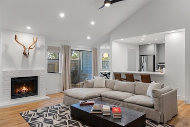 Living area with light wood finished floors, recessed lighting, ceiling fan, a warm lit fireplace, and high vaulted ceiling