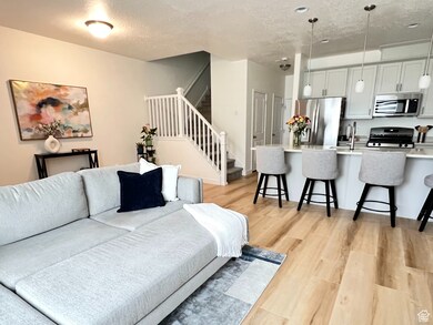 Living area featuring light wood-style flooring, stairs, and a textured ceiling