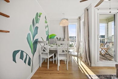 Dining area with a ceiling fan, light wood-style flooring, and ornamental molding