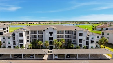 View of apartment building / complex with view of golf course, a water view, and covered parking