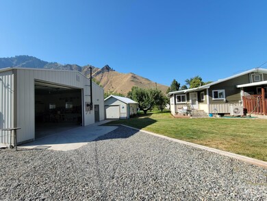 View of side of property with a mountain view, an outbuilding, a garage, a lawn, and gravel driveway