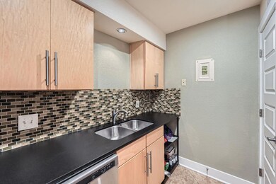 Kitchen featuring light brown cabinetry, dark cou