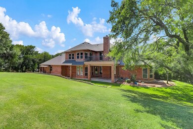 Back of house with brick siding, a yard, a chimney, and a balcony