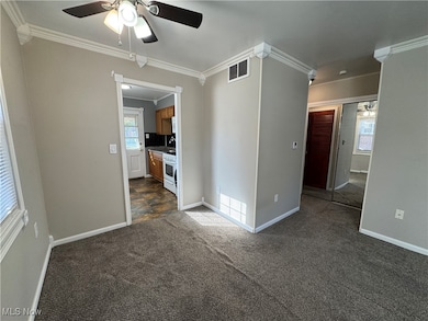 Dining area with a ceiling fan, crown molding, and dark carpet
