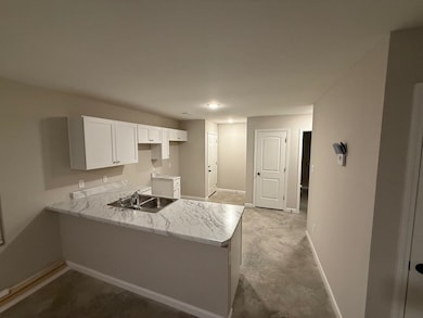 Kitchen featuring white cabinetry, sink, and kitchen peninsula