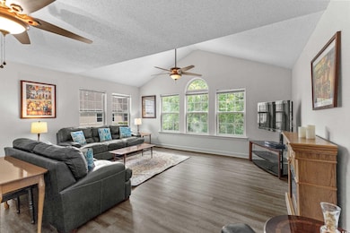 Living room with ceiling fan, wood finished floors, vaulted ceiling and baseboards
