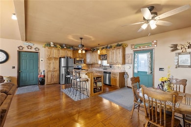 Kitchen featuring a kitchen breakfast bar, dark wood-style floors, appliances with stainless steel finishes, and ceiling fan