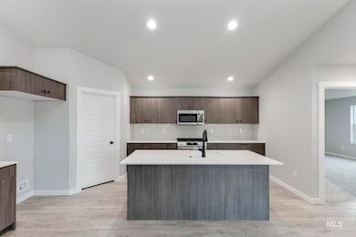 Kitchen featuring modern cabinets, a kitchen island with sink, decorative backsplash, dark brown cabinets, and recessed lighting