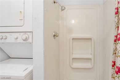 Full bathroom featuring stacked washer and clothes