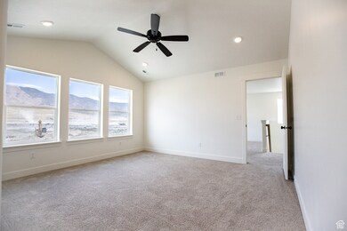 Primary bedroom with a generous vaulted ceiling, ceiling fan, and beautiful windows.