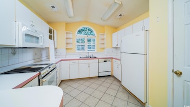 Kitchen with white appliances, a sink, open shelves, vaulted ceiling, and tasteful backsplash