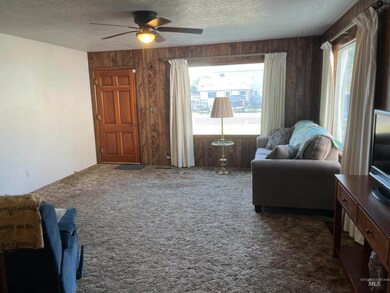 Living area featuring a ceiling fan, wood walls, dark colored carpet, and a textured ceiling