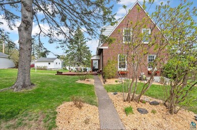 English style home featuring a deck, brick siding, and a front yard