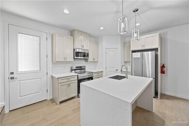 Kitchen with appliances with stainless steel finishes, a sink, light countertops, backsplash, and light wood-style flooring