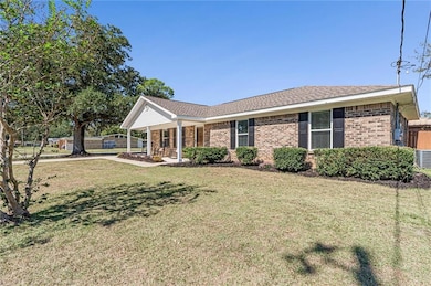 Single story home with a porch, a front yard, roof with shingles, and brick siding