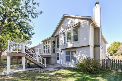 Back of property with stairway, a patio area, a chimney, and a wooden deck